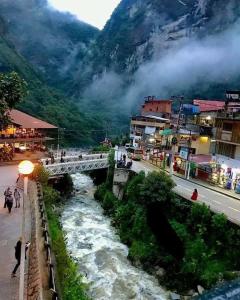 a bridge over a river in a town with a mountain at Hospedaje San Francisco in Machu Picchu