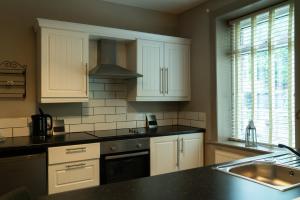a kitchen with white cabinets and a black counter top at The Milestone in Sowerby Bridge +7 photos