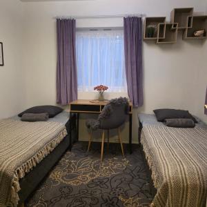 ein Zimmer mit zwei Betten und einem Schreibtisch und einem Fenster in der Unterkunft Nord Stay Tromso in Tromsø