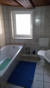 baño con bañera, aseo y ventana en Ferienwohnung Bernhardt, en Sarstedt