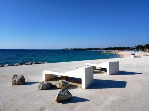 a white bench sitting on a beach next to the water at Villa Abelia in Medulin