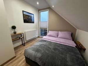 een slaapkamer met een bed met paarse lakens en een raam bij Dom "Między jeziorami" na Kaszubach, 10 osób, jacuzzi, ognisko, kominek in Grabówko