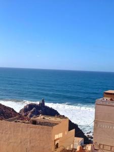 a view of the ocean with a building on a beach at Blue Wave Surf House in Mirleft