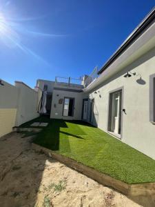 een huis met een tuin van groen gras bij Luxar Suites & Apartments in Assemini