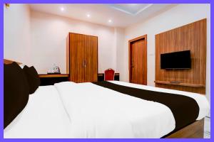 une chambre avec un lit blanc et une télévision à écran plat dans l'établissement Hotel Aaryex Premium Near Railway Station, à Bhubaneswar