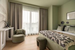 a bedroom with a bed and a chair and a window at Electra Apartments in Krakow +235 photos