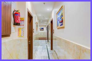 un couloir avec des sols en marbre et des murs avec des peintures dans l'établissement Hotel Aaryex Premium Near Railway Station, à Bhubaneswar