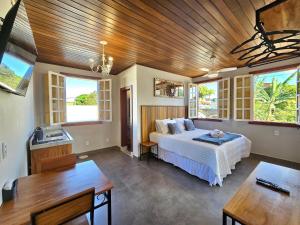 een slaapkamer met een bed in een kamer met ramen bij Vila Bella Suítes - Conforto no Centro in Carrancas