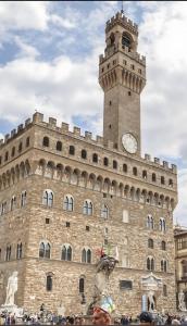 ein großes Gebäude mit einem Uhrturm darauf in der Unterkunft Romantica Suite nel cuore Firenze in Florenz