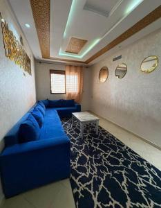 een woonkamer met een blauwe bank en een tafel bij Résidence Al Manadir Agadir in Aourir