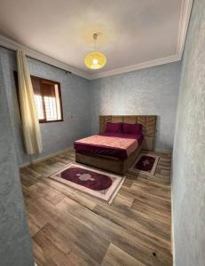 een slaapkamer met een bed en twee tapijten erin bij Résidence Al Manadir Agadir in Aourir