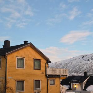 ein Holzhaus mit einem schneebedeckten Berg im Hintergrund in der Unterkunft Nord Stay Tromso in Tromsø