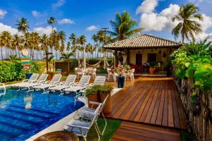eine Holzterrasse mit Stühlen und einem Pool in der Unterkunft Reserva do Paiva suites in Cabo de Santo Agostinho