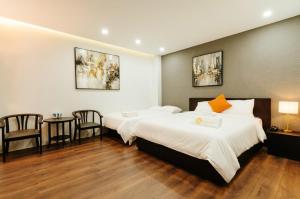 twee bedden in een kamer met een tafel en stoelen bij Annam Saigon Home in Ho Chi Minh-stad