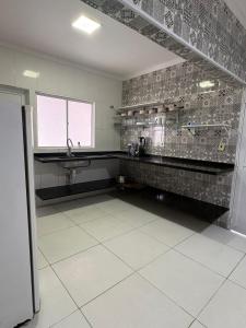 een keuken met een wastafel en een tegelvloer bij Casa Cacau in Ubatuba