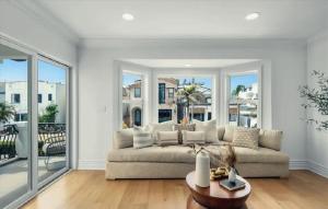 een woonkamer met een bank en grote ramen bij Expansive Five Bedroom Beachside Home with Generous Living Space in Hermosa Beach