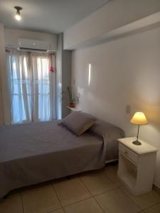 een slaapkamer met een bed met een raam en een lamp bij Monoambiente Avellaneda Barrio Norte in San Miguel de Tucumán