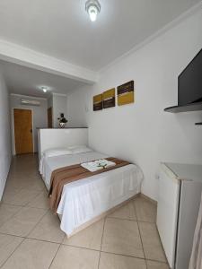 een slaapkamer met een bed en een flatscreen-tv bij Pousada Mar Alto in Ilha Comprida