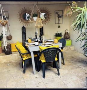 ein Esstisch und Stühle mit gelben Kissen in der Unterkunft Maison de village familiale Sablet in Sablet
