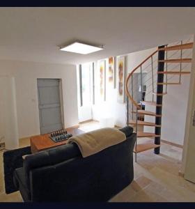 ein Wohnzimmer mit einem Sofa und einer Wendeltreppe in der Unterkunft Maison de village familiale Sablet in Sablet