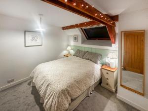een slaapkamer met een bed en een tv aan de muur bij Pilsbury Cottage in Luppitt