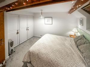 een slaapkamer met een groot bed en witte kasten bij Pilsbury Cottage in Luppitt
