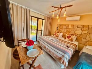 ein Hotelzimmer mit einem Bett und einem Tisch mit Blumen darauf in der Unterkunft Reserva do Paiva suites in Cabo de Santo Agostinho