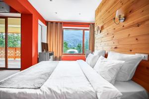 クラースナヤ・ポリャーナにあるPark Chalet Residenceの木製の壁のベッドルーム1室(白い大型ベッド1台付)