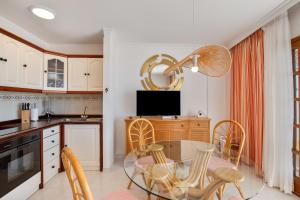 een keuken met een glazen tafel met stoelen en een televisie bij Playa Delphin 105 in Puerto Naos +24 foto's