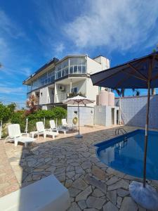 a building with a pool and chairs and an umbrella at Pousada Mar Alto in Ilha Comprida