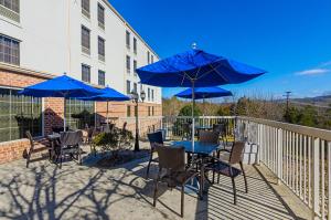 eine Terrasse mit Tischen, Stühlen und blauen Sonnenschirmen in der Unterkunft Holiday Inn Express Lexington by IHG in Lexington