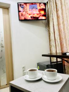 two cups of coffee on a table with a tv at CityCenter Studio in Chişinău +2 photos