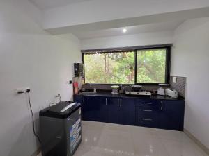 a kitchen with blue cabinets and a large window at Square Greens in Siolim