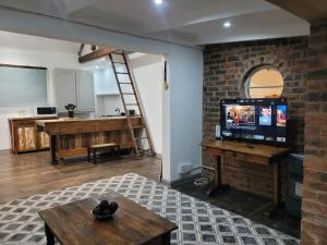 een woonkamer met een televisie en een bakstenen muur bij Lionsgate Estate Cottage in Dargle