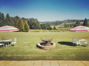 een park met twee tafels, twee parasols en een fontein bij Lionsgate Estate Cottage in Dargle