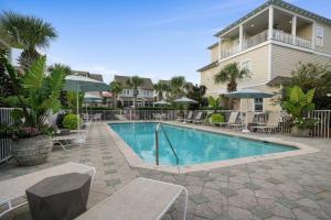 a swimming pool with chairs and umbrellas next to a building at Arrabella - Gulf Views with Deck & Community Pool in Santa Rosa Beach