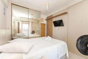 ein Schlafzimmer mit einem weißen Bett und einem Spiegel in der Unterkunft Edifício La Tour Residence | Centro – Curitiba in Curitiba + 25 Fotos
