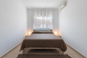 ein Schlafzimmer mit einem Bett und einem Fenster in der Unterkunft Bungalow - Playa Maspalomas in San Bartolomé de Tirajana