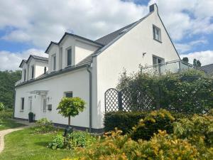 a white house with a fence in a yard at "Villa Harmonie" direkt am Golfplatz in Göhren-Lebbin
