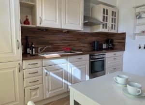 een keuken met witte kasten en een wit aanrecht bij Ferienwohnung Medemspeicher in Otterndorf