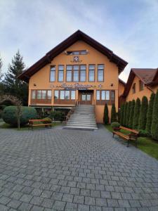 een groot gebouw met twee banken ervoor bij Pensiunea Casa Barsan in Bîrsana