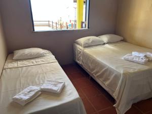 two beds in a room with white sheets and towels at Duplex Morro de São Paulo in Cairu +5 photos