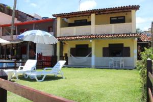 two chairs and an umbrella in front of a house at Duplex Morro de São Paulo in Cairu