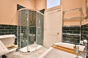 a bathroom with green tiled walls and a toilet and a tub at 1 Purfleet Quay in King's Lynn