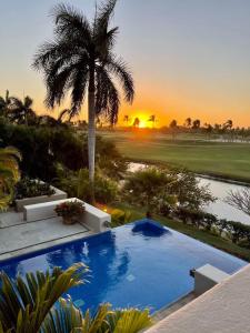 a resort pool with a palm tree and a sunset at Lagos Del Mar - Casa Dos Vistas in Punta Mita