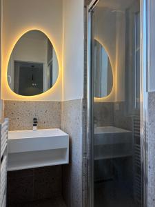 a bathroom with a sink and a shower with two mirrors at Charmant T2 in Alfortville