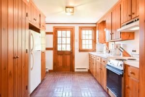 a kitchen with wooden cabinets and a white refrigerator at Walk to Water w Stunning Cove Views in Eastham