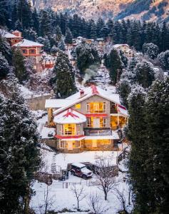 een huis met een auto in de sneeuw bij The ForestBound Cottage in Manāli