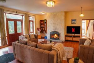 een woonkamer met een bank en een open haard bij The ForestBound Cottage in Manāli