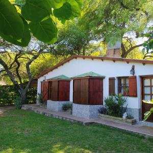 een wit huis met houten deuren en een boom bij Casa cercana a plaza de Villa de las Rosas con patio y asador in Villa Las Rosas